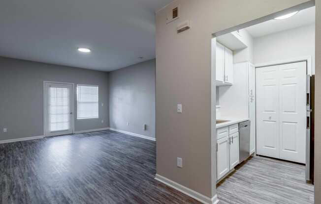 an empty living room and kitchen with white doors