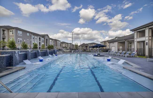 an outdoor pool with lounge chairs and buildings around it