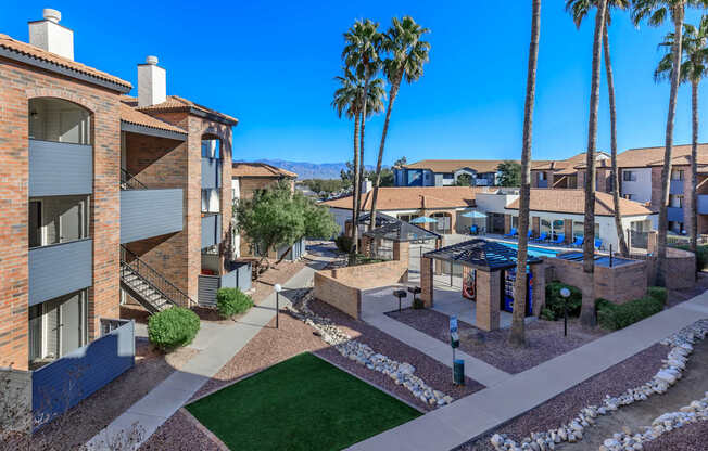 A sunny day at a residential complex with a pool and palm trees.