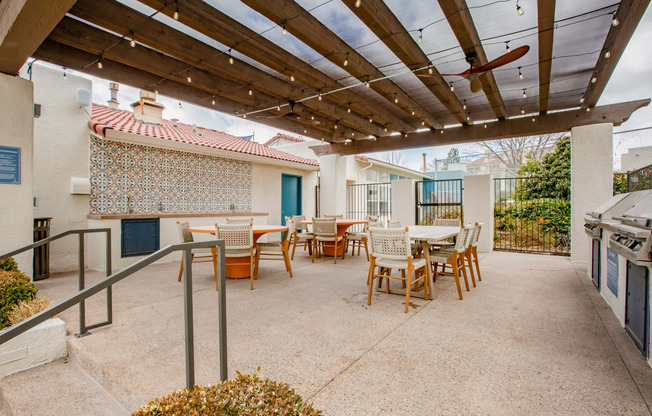 a patio with tables and chairs and a grill