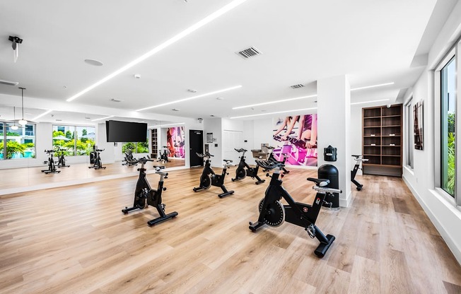 a spacious fitness center with a wood floor and white walls