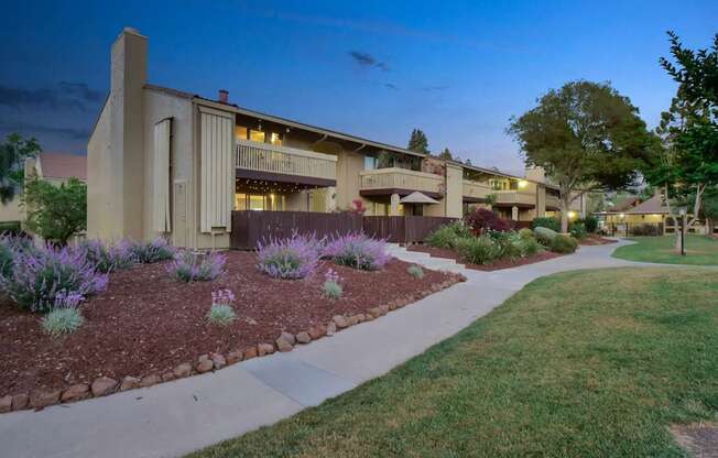 a building with a sidewalk and a garden in front of it at Summerwood Apartments, California