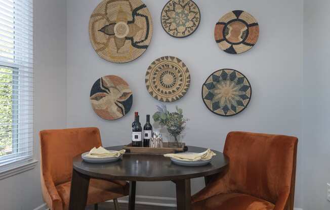 a dining area Seasons at Umstead apartments in Raleigh with a table and two orange chairs