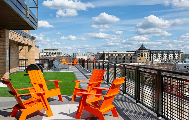 A patio with orange chairs and a view of the city.