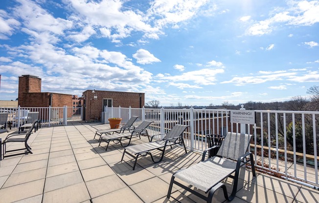 A sunny day on a balcony with chairs and a warning sign.