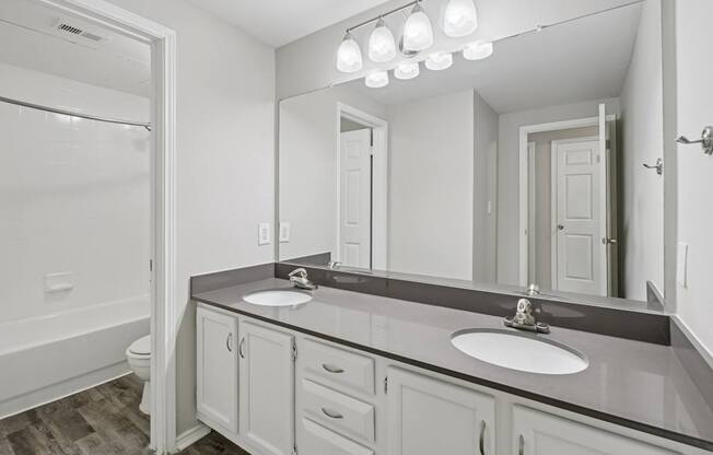 A bathroom with a sink, mirror, and a tub.