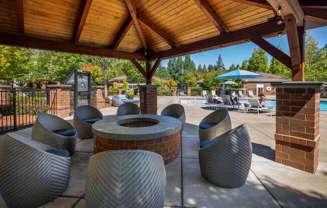 A group of grey chairs are arranged under a wooden roof.