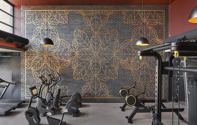 a gym with exercise machines in front of a wall with a gold leaf mural