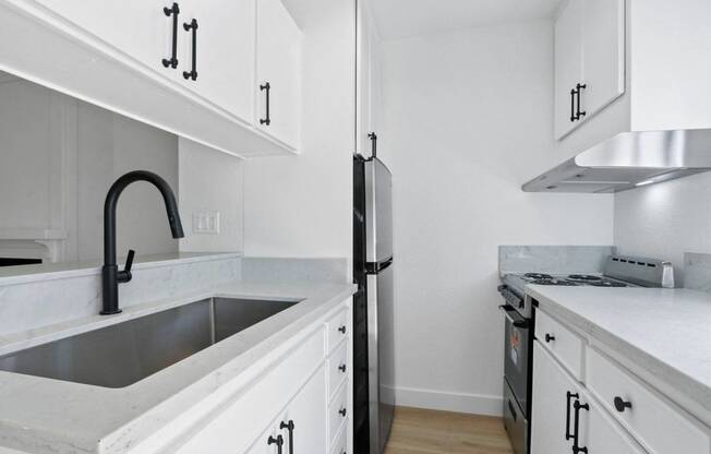 a kitchen with white cabinets and a sink and a refrigerator