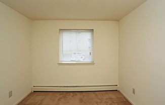 the upstairs bedroom has a large window and beige walls