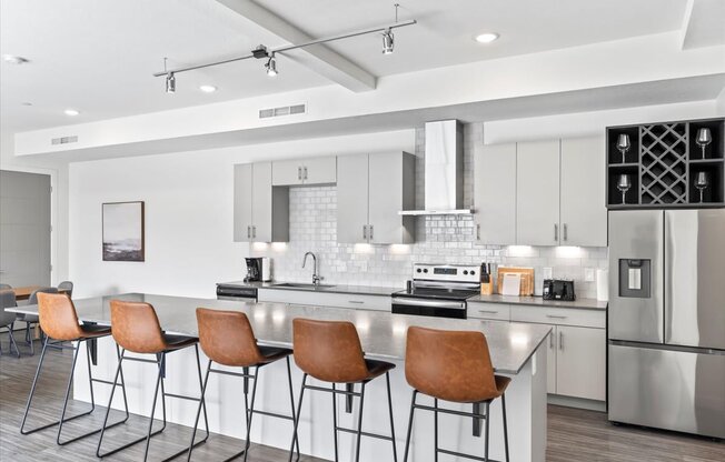 A modern kitchen with a bar area and chairs.