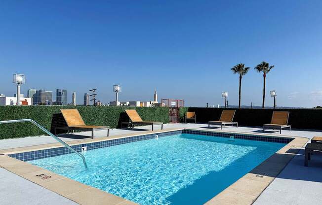 Swimming pool with lounge chairs and palm trees.