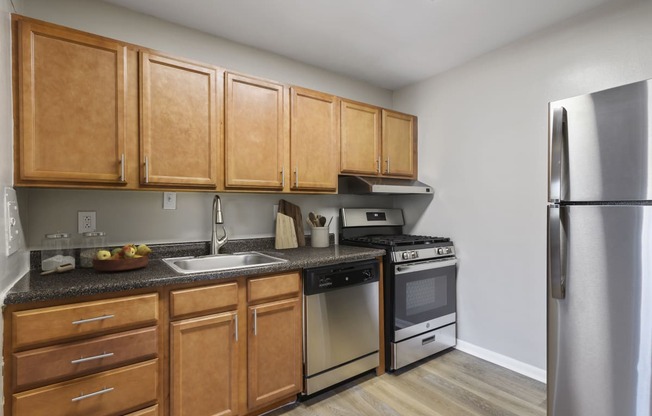 an empty kitchen with wooden cabinets and stainless steel appliances