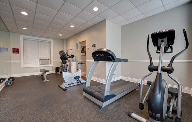 A gym with a treadmill, elliptical trainer and a stationary bike.
