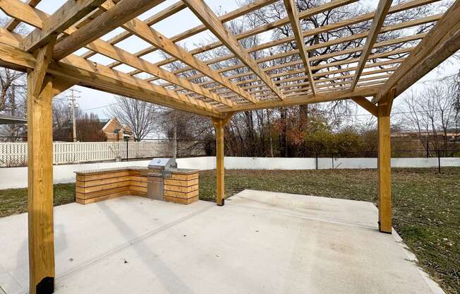 a patio with a wooden structure and a fire pit