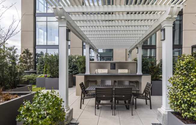 a pergola over a table and chairs on a patio in front of a building