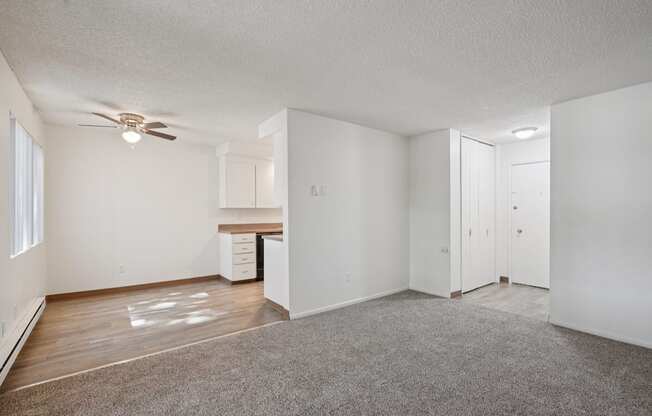 A spacious room with a ceiling fan and a kitchenette.