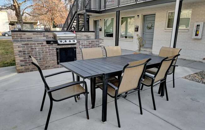 a patio with a table and chairs and a grill