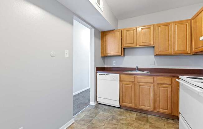 an empty kitchen with wooden cabinets and white appliances