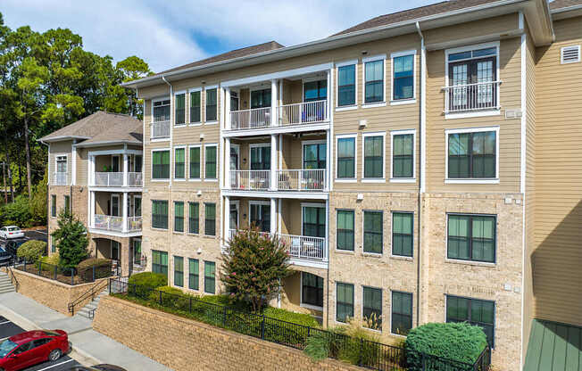 A multi-story apartment building with a red car parked in front.