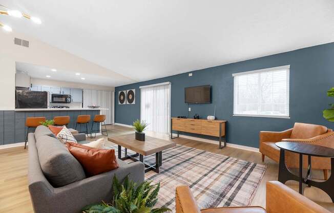 A living room with a grey couch, a wooden coffee table, and a flat screen TV mounted on the wall.
