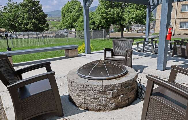 A patio with a fire pit and chairs.