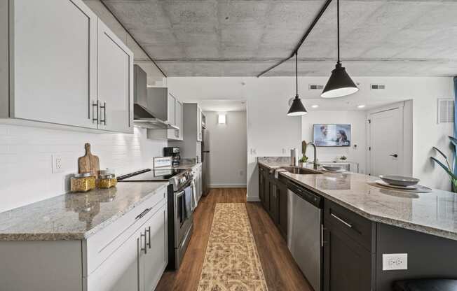 a kitchen with white cabinets and a large island with granite countertops  at The Icon, Richmond, Virginia