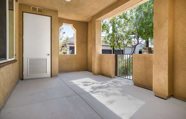 a patio with a white door and a tree in the background