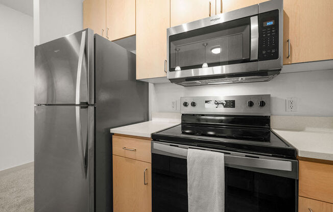 A kitchen with a stainless steel refrigerator, black stove, and microwave above it.