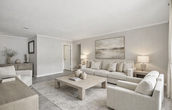A living room with a grey couch, a coffee table, and a painting on the wall.