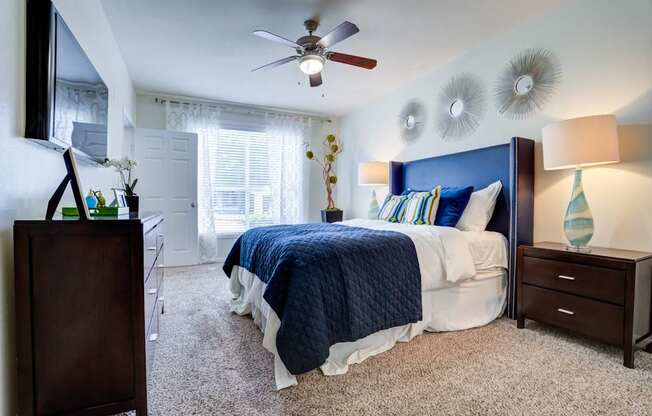 A bedroom with a bed, nightstand, and a ceiling fan.