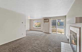 an empty living room with a fireplace and a door to a balcony