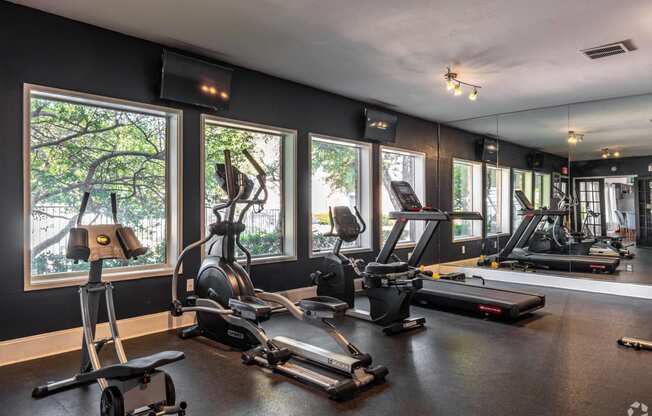 the gym has plenty of exercise equipment and views of the trees