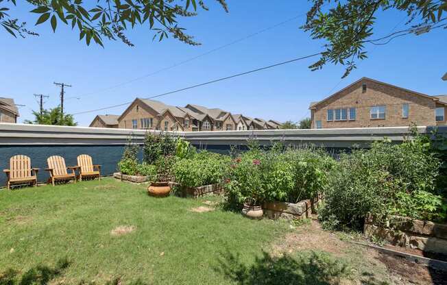 A garden with a lawn, a few chairs, and apartments in the background at Encore at Buckingham Apartments in Richardson, TX
