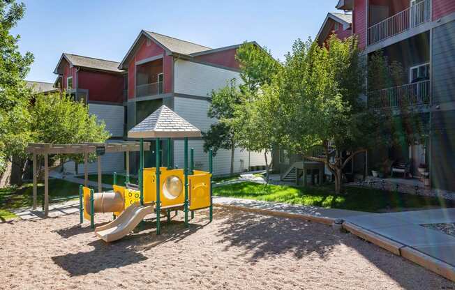 a playground with a yellow play set in front of an apartment building at Stetson Meadows Apartments, Colorado Springs, CO