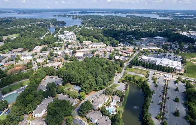 A bird's eye view of a residential area with a lake and a large building in the distance.