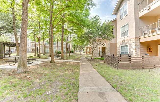 A tree-lined sidewalk in front of apartment buildings.