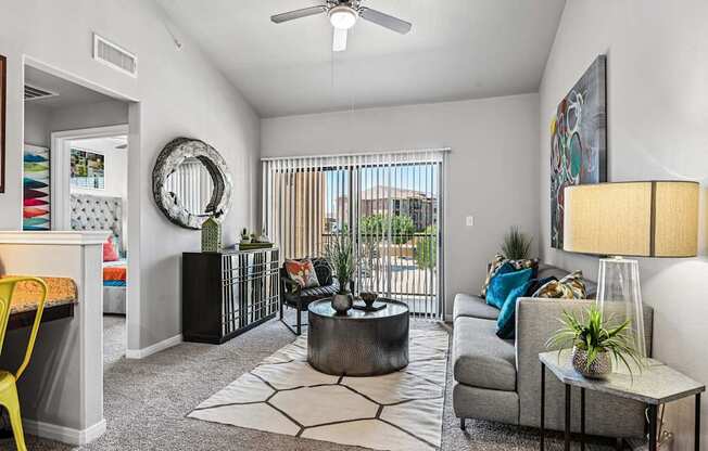 A living room with a grey couch, a yellow chair, and a white ceiling fan.