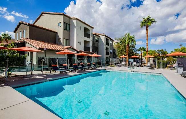 Colton Apartments large sparkling pool with seating with umbrellas