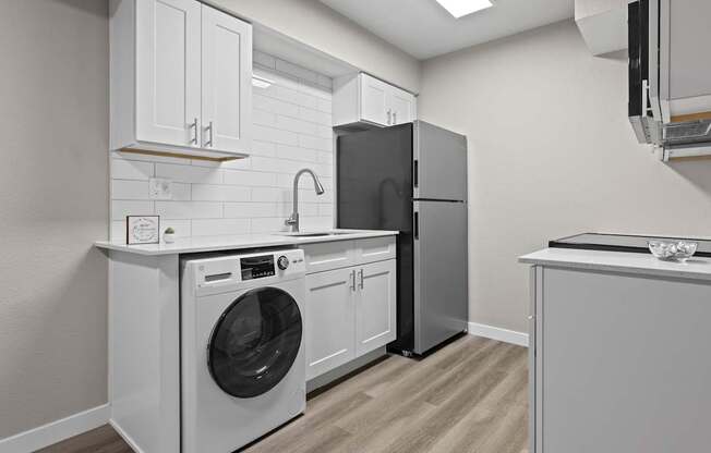 A modern kitchen with a washing machine and a refrigerator.