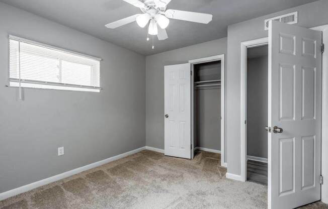 A room with a ceiling fan and three doors.