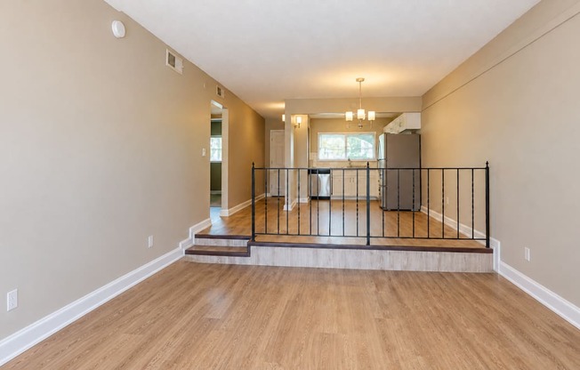 Unfurnished living room with steps and a railing separating the raised dining area at Waterchase Apartments in Largo, FL.