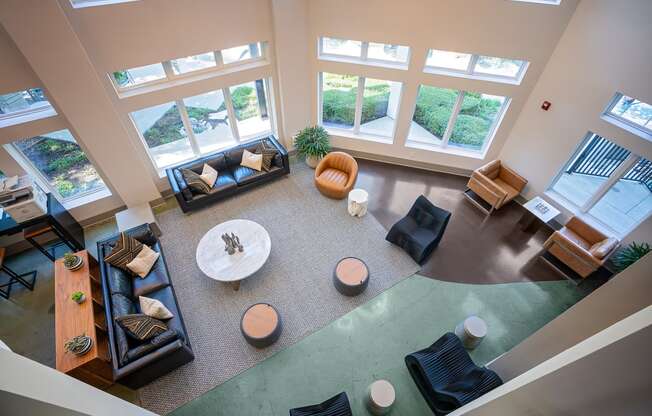 View of lobby from above with chairs and couches and tables with lots of windows.