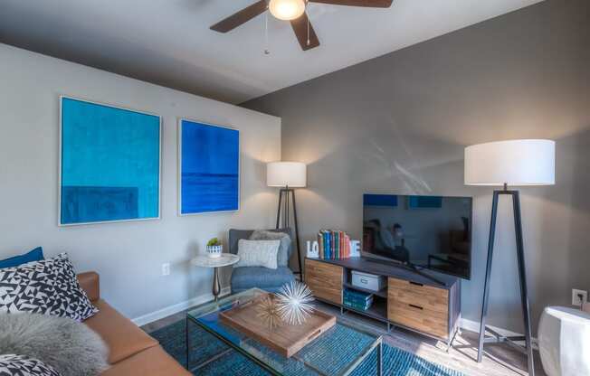 a living room with a ceiling fan and a flat screen tv