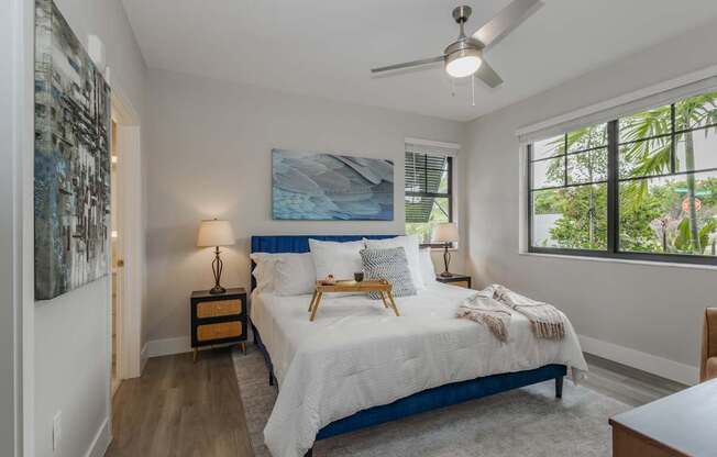 A bedroom with a bed, nightstand, and a painting on the wall.