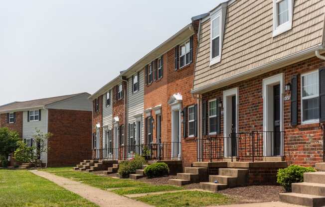 a row of brick apartments with steps and grass in front of them