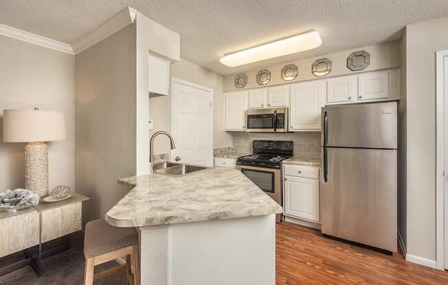 a kitchen with stainless steel appliances and a marble counter top at Highland Ridge Apartments, Overland Park , KS