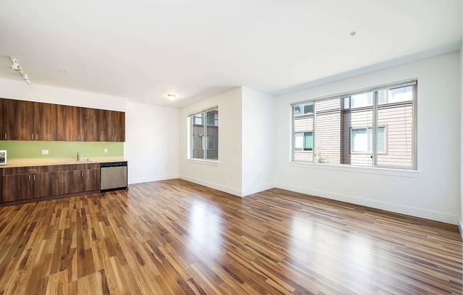 an empty living room with wood flooring and a window