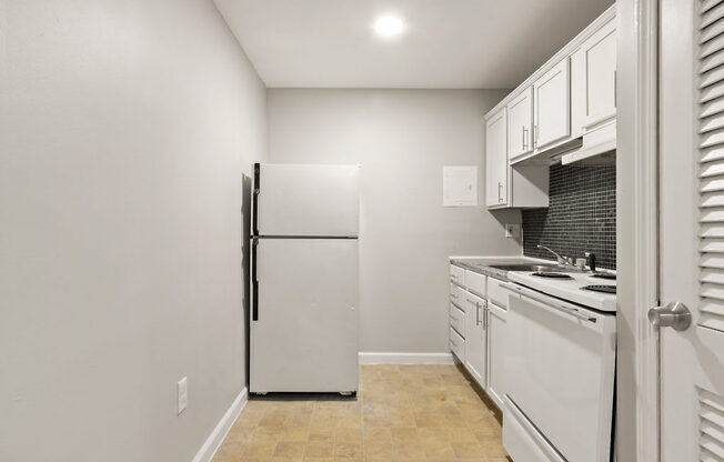 a kitchen with white cabinets and a refrigerator