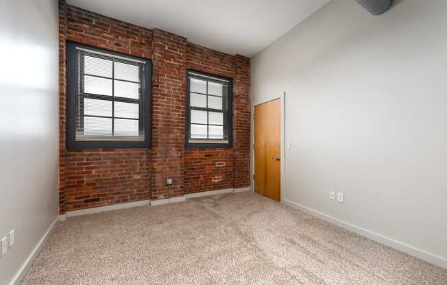 an empty room with a brick wall and a door and a window